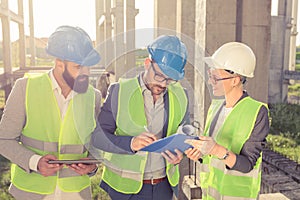 Group of architects or business partners having a meeting and signing documents on a construction site