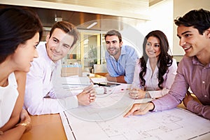 Group Of Architects Discussing Plans In Modern Office