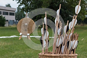 Group of Arrows inside Wicker Basket and Straw Archery Target in