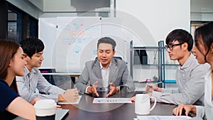 Group of Asian business people discuss together in team brainstorm meeting, work late night in office