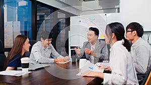 Group of Asian business people discuss together in team brainstorm meeting, work late night in office