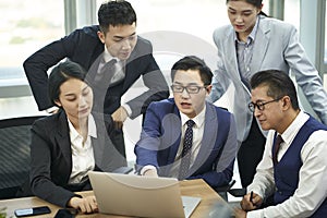 group of asian business people having a discussion using laptop computer