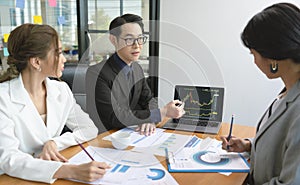 Group of Asian business people meeting about business plan and present and explain stock financial chart from laptop computer at