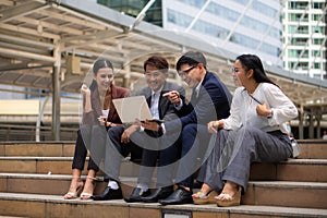 Group of asian business people sitting together outdoor with laptop computer