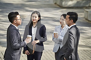 Group of asian business people standing chatting on street