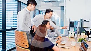 Group of Asian business people work together in team brainstorm discussion on desktop computer in office