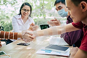 Group Asian businessmen and women shake hands together to create a mutually beneficial business relationship. The economic graph