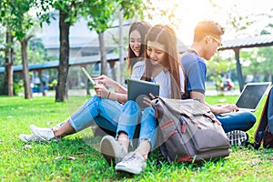 Group of Asian college student using tablet and laptop on grass