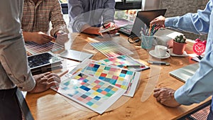 Group of Asian designers brainstorming working together with colleagues and color swatches in co-working workplace