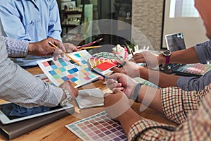 Group of Asian designers brainstorming working together with colleagues and color swatches in co-working workplace