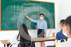 Group of Asian elementary school students and teacher wearing hygienic mask to prevent the outbreak of Covid 19 in classroom while