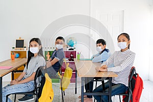 Group of Asian elementary school students wearing hygienic mask in classroom and smiling to be happy while back to school reopen
