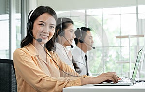 Group of Asian employee work in telemarketing customer service teams. Young operator woman working with headset smiling