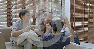 Group of asian flat mates watching sports competition on TV at home.