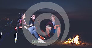 A group of Asian friends tourist drinking and playing guitar together with happiness in Summer while having camping near lake at