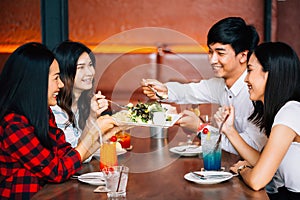 Group of Asian happy and smiling young man and women having a meal together with enjoyment and happiness.