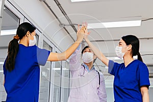 Group of Asian medical professional staff in uniform putting unity hands up together at hospital. Male doctor and two