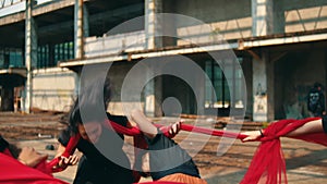 a group of Asian men are playing with red cloth ropes with their friends in a tug of war