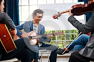 A group of Asian musicians playing guitar and violin sitting on classical music.