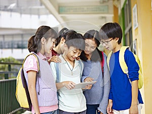 Group of asian pupils using tablet computer at school