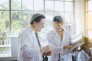 Group of asian scientist working and analyzing data research information together in the laboratary