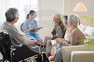 Group of Asian senior people sit in a circle in a nursing home and listen to nurse during a group elderly therapy session.