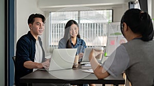 A group of Asian startup businesspeople are discussing a new project in the meeting room together