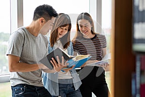 Group of asian students researching data for homework assignment in library