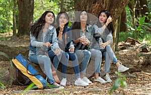 Group of Asian teenage girls camping in the forest and was sitting, relaxing, drinking water happily