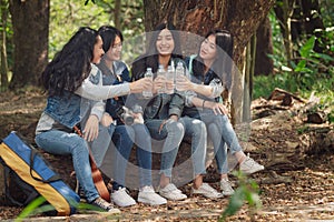 Group of Asian teenage girls camping in the forest and was sitting, relaxing, drinking water happily