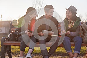 Group of Asian teenage students schoolchildren sitting on a bench in the park and preparing exams