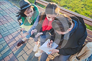 Group of Asian teenage students schoolchildren sitting on a bench in the park and preparing exams