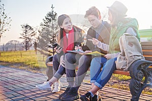 Group of Asian teenage students schoolchildren sitting on a bench in the park and preparing exams