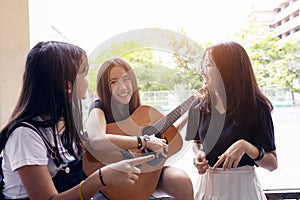 Group of asian teenager standing outdoor plying spanish guitar and dancing with happiness emotion photo