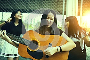 Group of asian teenager standing outdoor plying spanish guitar and dancing with happiness emotion