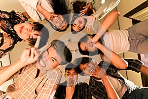 a group of Asian teenagers forming a circle and looking down with funny faces in an old room