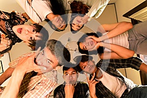 a group of Asian teenagers forming a circle and looking down with funny faces in an old room