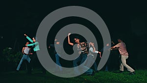 a group of Asian teenagers playing and dancing together in the dark of night