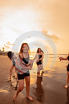 a group of Asian teenagers running with happy expressions on vacation with their friends drunk on the beach