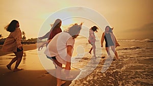 a group of Asian teenagers in shirts playing on the beach with their friends happily