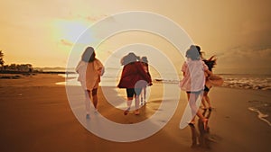 a group of Asian teenagers in shirts playing on the beach with their friends happily