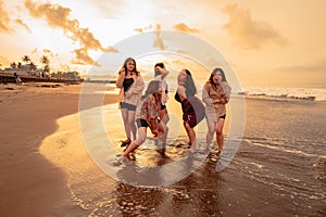 a group of Asian women enjoying their holiday very crazy with their friends and with a full expression of silliness on the beach photo