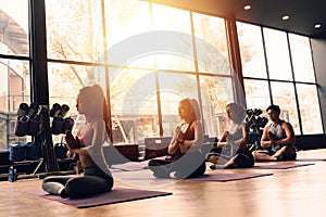 Group of Asian women and man doing pilates lying on yoga mats in aerobics class. Young sporty people on crossed legs on