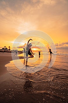 a group of Asian women is standing on the beach in black clothes and doing ballet moves in unison