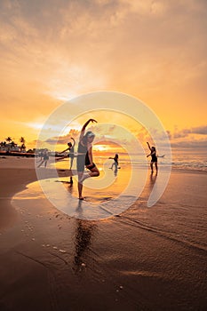 a group of Asian women is standing on the beach in black clothes and doing ballet moves in unison