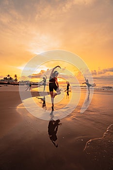 a group of Asian women is standing on the beach in black clothes and doing ballet moves in unison