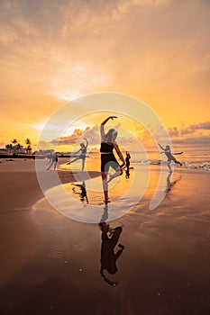 a group of Asian women is standing on the beach in black clothes and doing ballet moves in unison