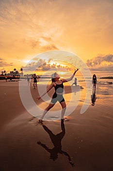 a group of Asian women is standing on the beach in black clothes and doing ballet moves in unison