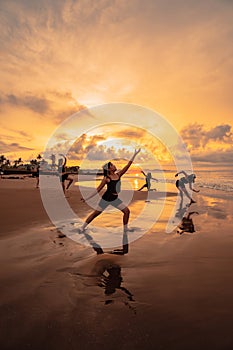 a group of Asian women is standing on the beach in black clothes and doing ballet moves in unison