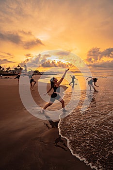 a group of Asian women is standing on the beach in black clothes and doing ballet moves in unison